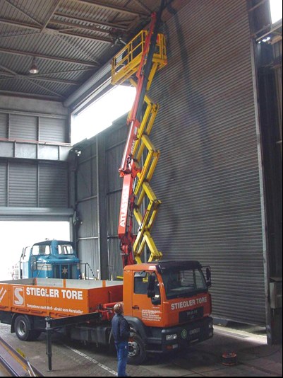 Servicetechniker auf einer Hebebühne bei der Reparatur eines großen Rolltors